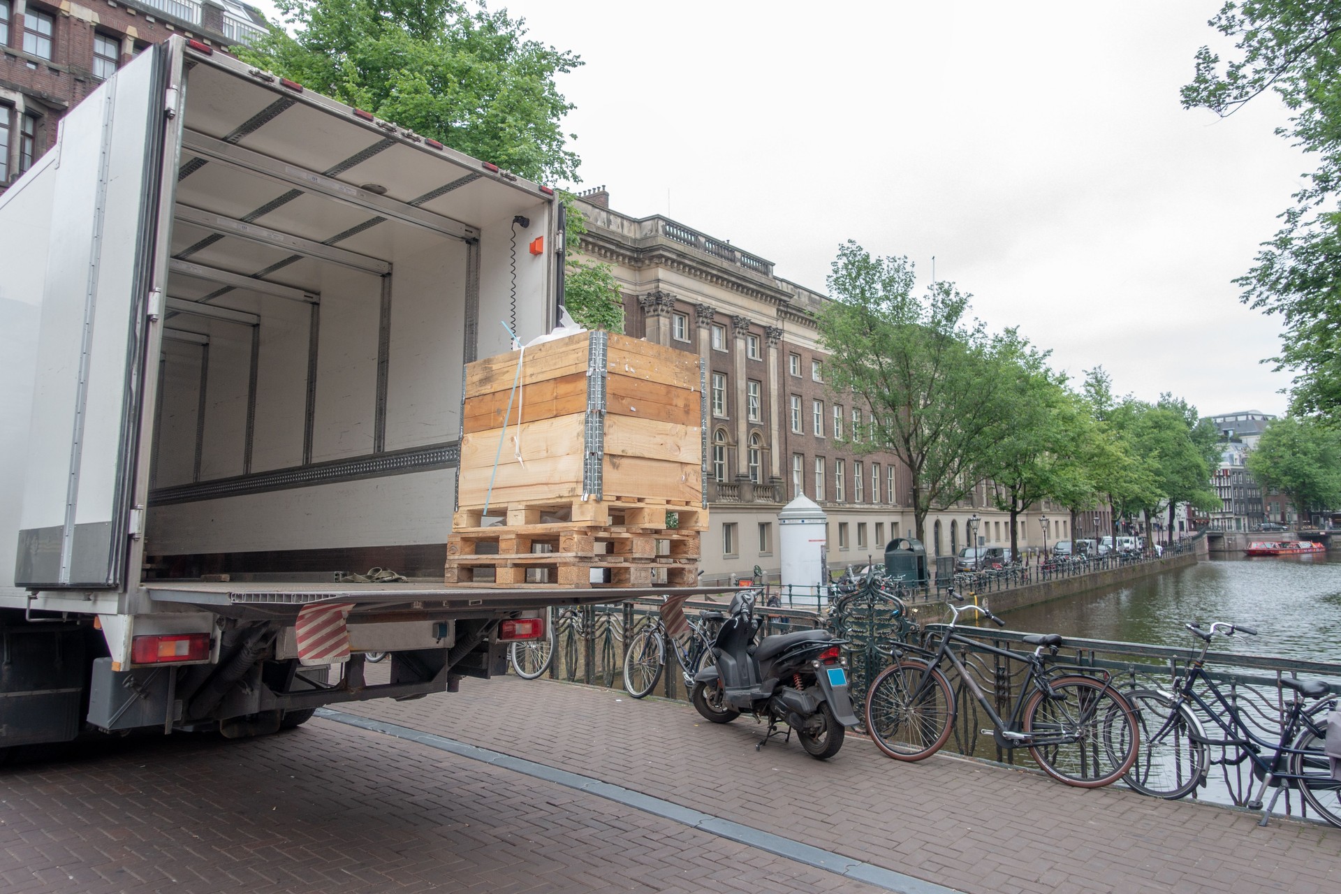 Small white truck unloading on Amsterdam canal bridge